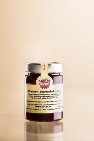 Ein Glas „Trüffelmarmelade“ mit goldenem Deckel und Etikett steht aufrecht auf einer reflektierenden Oberfläche vor einem neutralen Hintergrund.